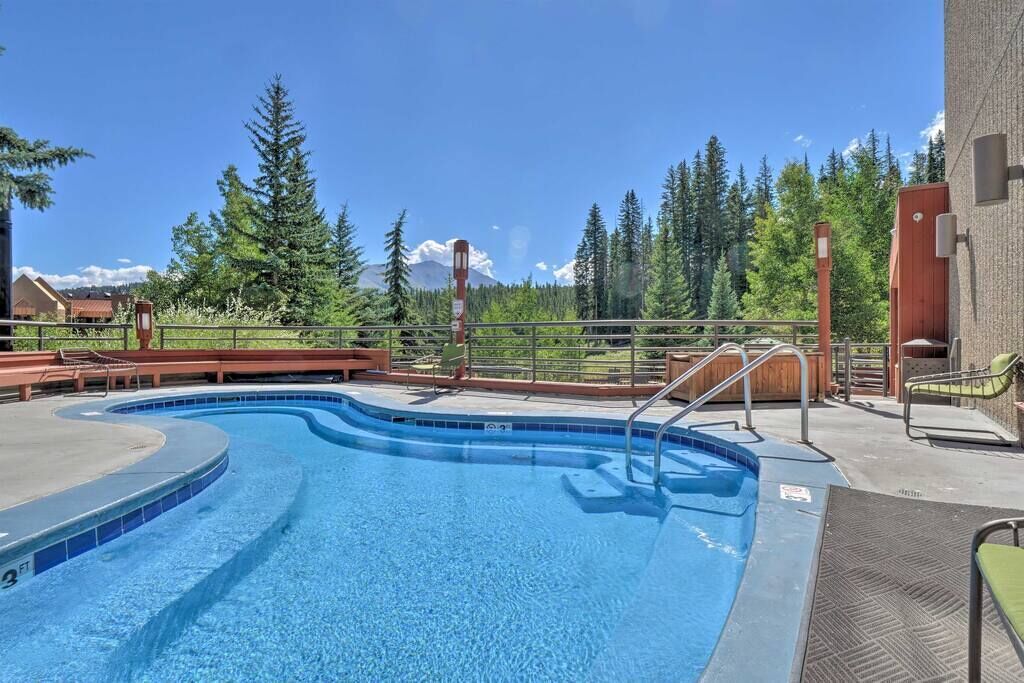 A swimming pool with a curved edge, surrounded by a wooden deck and metal railings.