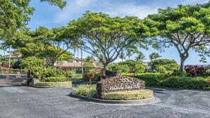 A landscaped area with a sign reading "WaiKolei Beach Villas" surrounded by trees and shrubs.