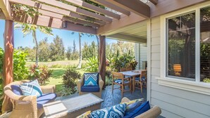A covered patio with wicker furniture, a table, and chairs.