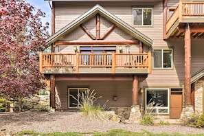 A two-story building with a stone foundation, a wooden balcony, and a large window.