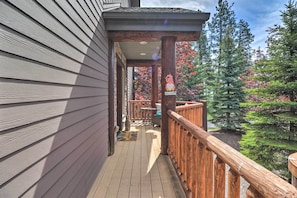 A wooden deck with a wooden railing, a welcome sign, and a view of trees.