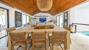 A spacious dining area with a large wooden table, woven chairs, and a unique ceiling light fixture.