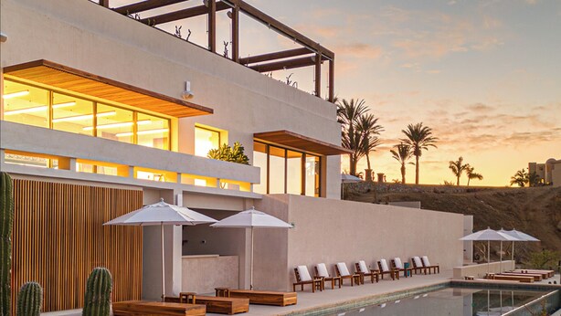 A modern resort with a pool, lounge chairs, and umbrellas.