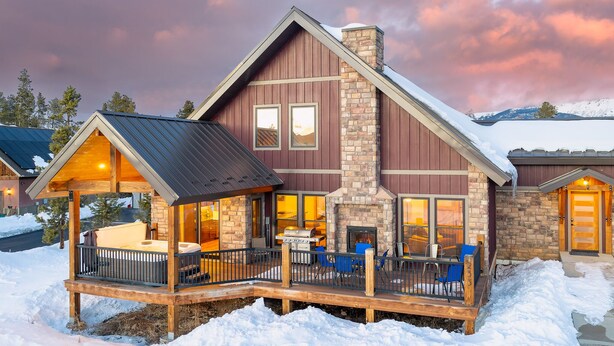 Un chalet doté d’une cheminée en pierre, de coins salon extérieurs et d’une terrasse couverte.