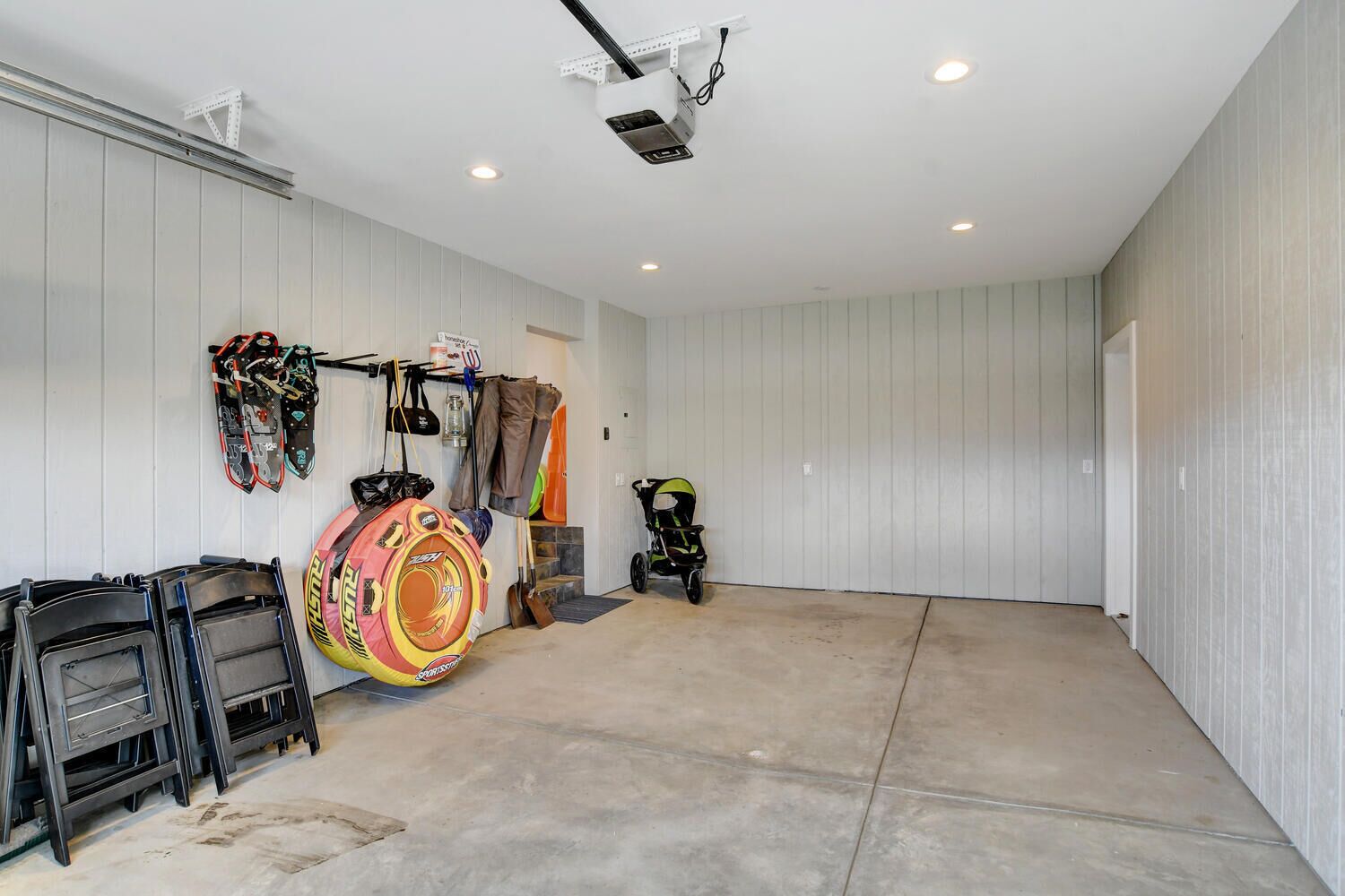 A garage with a concrete floor, white walls, and a ceiling-mounted projector.