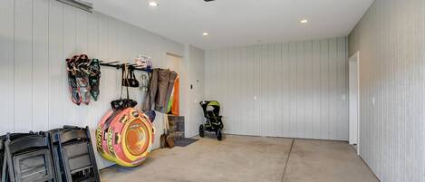 A garage with a concrete floor, white walls, and a ceiling-mounted projector.