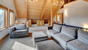 Une pièce spacieuse de style loft, avec de hauts plafonds, des poutres apparentes et une grande fenêtre.