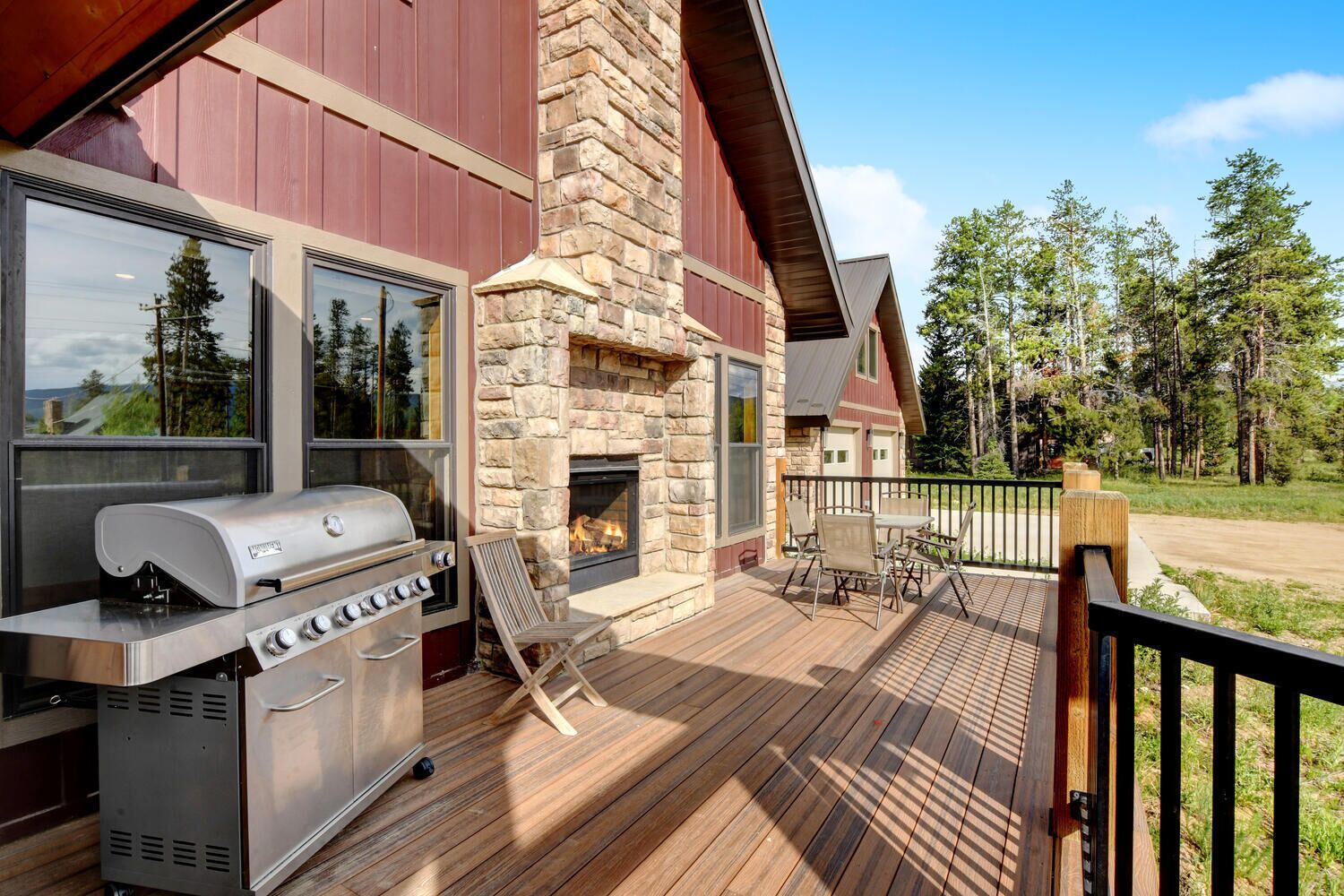 A deck with a stone fireplace, a grill, and outdoor furniture.