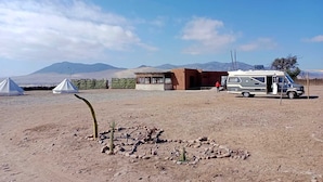 Un camping con tiendas de campaña, un edificio pequeño y una autocaravana.
