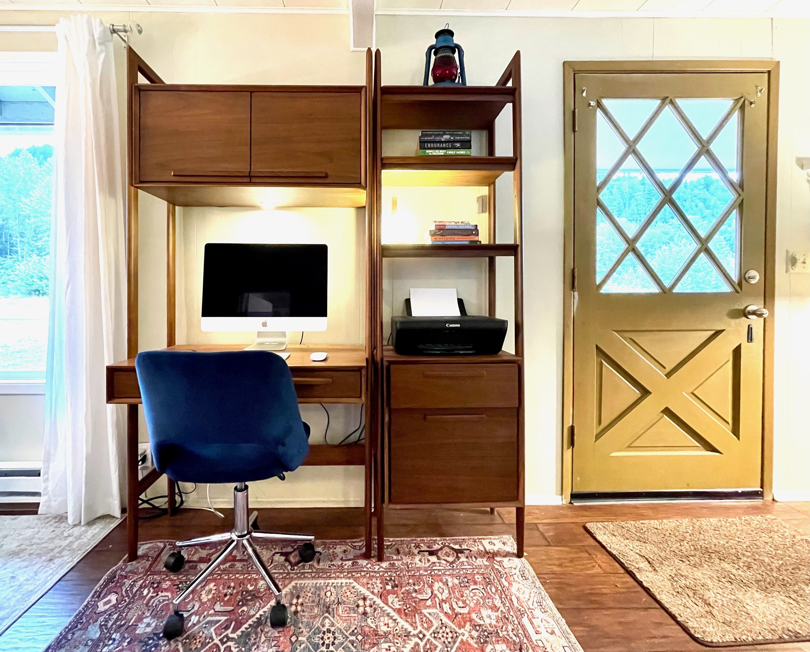 A home office with a desk, computer, chair, and shelves.