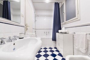 Een bad/douchecombinatie, een haardroger, een bidet, handdoeken