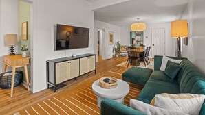 A modern living room with a green sofa, a white coffee table, and a flat-screen TV mounted on the wall.
