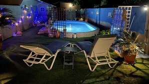 Ein Garten mit Schwimmbad, zwei Liegestühlen und einem kleinen Tisch.