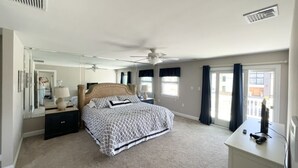 Ein Schlafzimmer mit Bett, Nachttischen, Deckenventilator und Kommode.