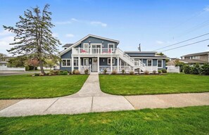 A two-story house with a front porch, a staircase leading to the second floor, and a well-maintained lawn.