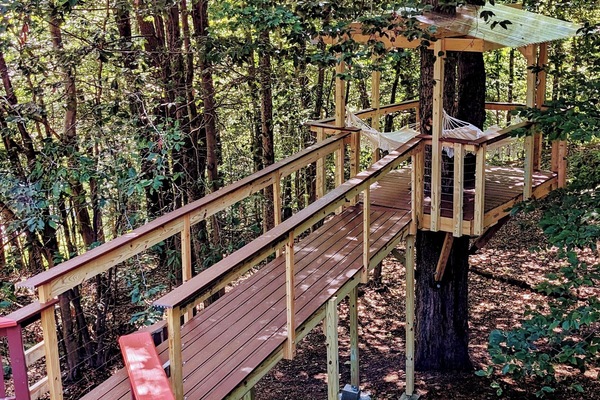 Breathtaking treehouse deck with hanging hammocks surrounded by woods