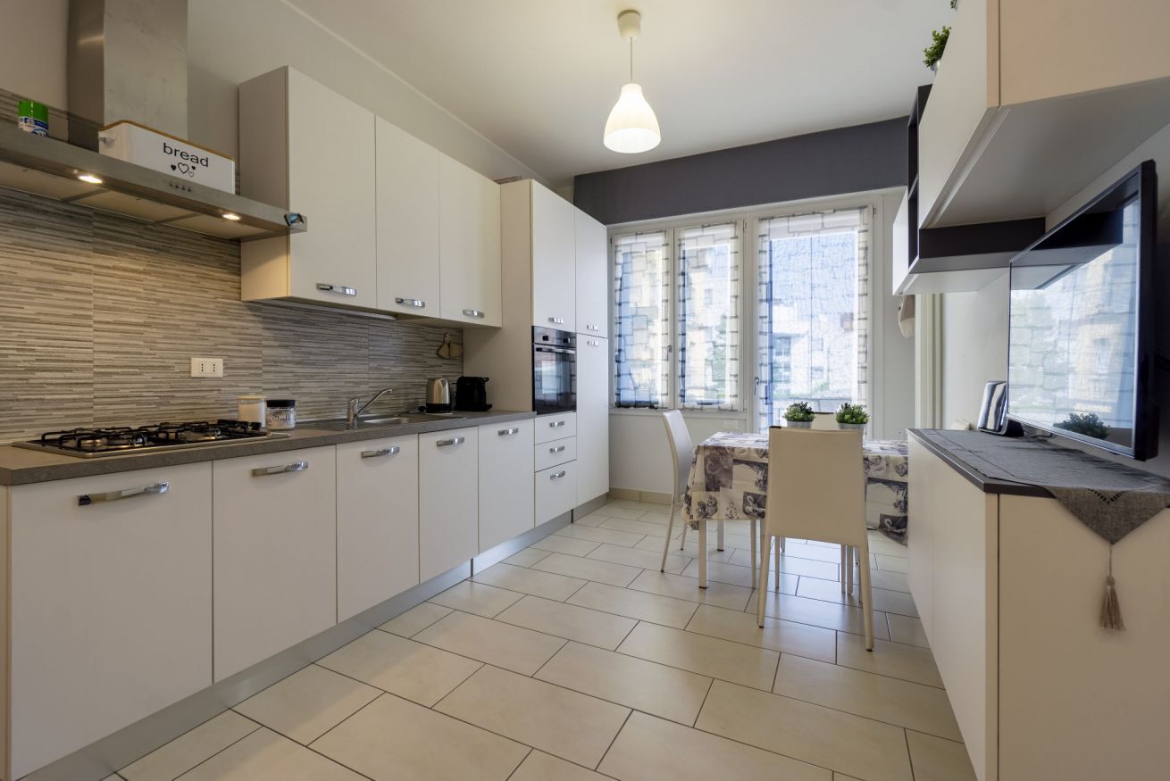 Een koelkast, een oven, een kookplaat, kookgerei, borden en bestek