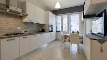 Een koelkast, een oven, een kookplaat, kookgerei, borden en bestek