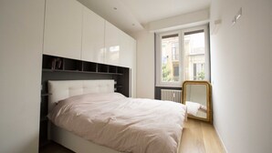 A bedroom with a bed, built-in wardrobe, a window with a view, and a mirror. - GetTheKey Monte Ceneri Apartment (Milano)