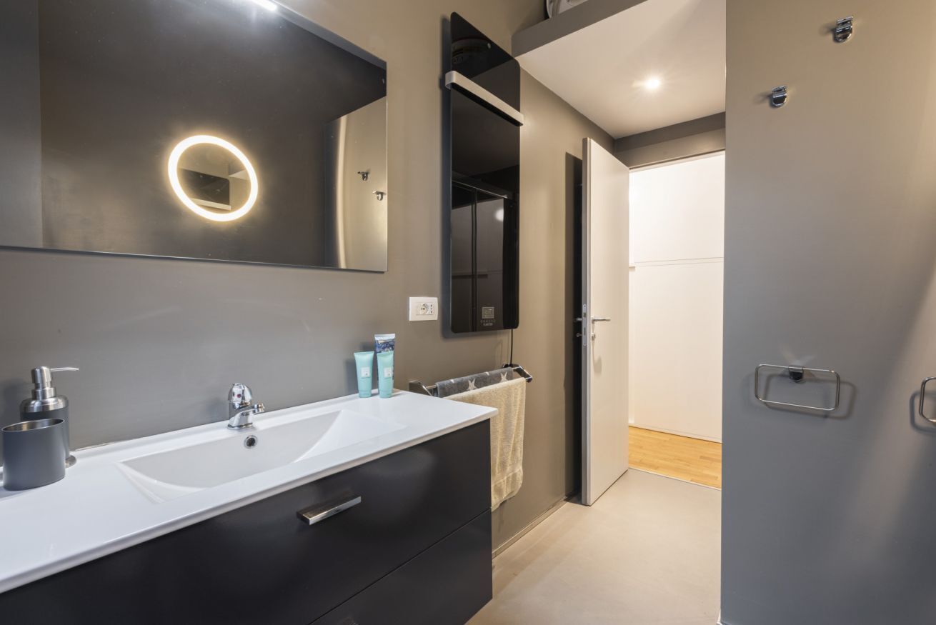 A modern bathroom with a large mirror, two sinks, and a towel rack.