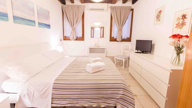 Ein Schlafzimmer mit einem Bett, einem Fernseher, einem Schreibtisch und einem Sessel.