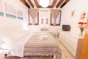 A bedroom with a bed, a TV, a desk, and a chair.
