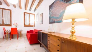 Ein Zimmer mit einem Holzkasten, einem roten Sofa, einem Esstisch mit Stühlen und einer Karte an der Wand.