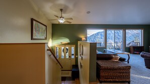 A spacious living area with a view of mountains, a fireplace, and a cozy seating area. - HIlltop Haven (Juneau)