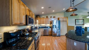 A modern kitchen with wooden cabinets, stainless steel appliances, and a granite countertop. - HIlltop Haven (Juneau)