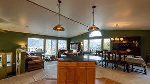 A spacious kitchen with a large island, wooden cabinets, and pendant lighting. - HIlltop Haven (Juneau)