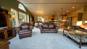 A spacious living room with leather armchairs, a coffee table, and a TV. - HIlltop Haven (Juneau)