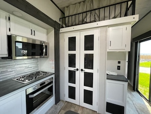 Enjoy cooking in this kitchen with an oven and stainless steel range hood, opening to a balcony with a view.