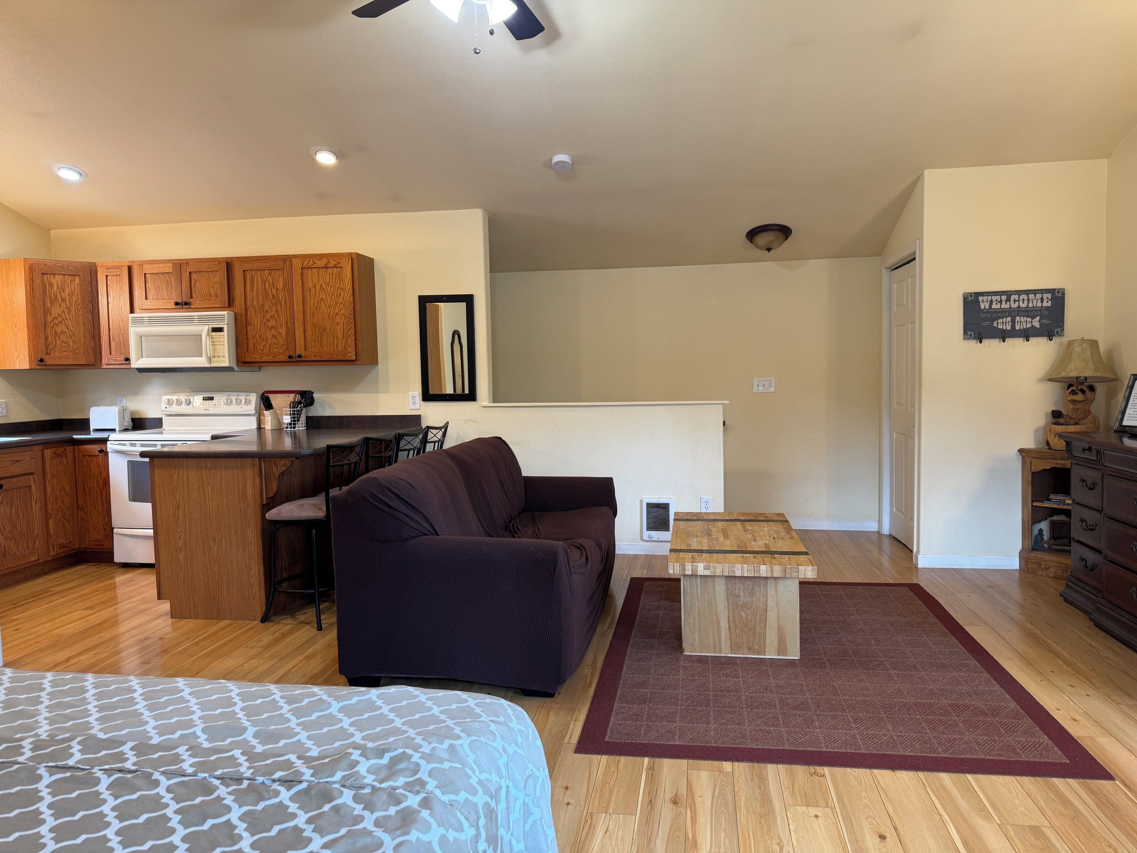 A compact living space with a kitchenette, a sofa, a coffee table, and a bed.