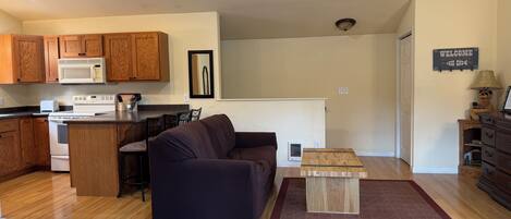 A compact living space with a kitchenette, a sofa, a coffee table, and a bed.