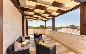 Une terrasse extérieure avec des meubles en osier, une vue sur la mer et un plafond à carreaux.