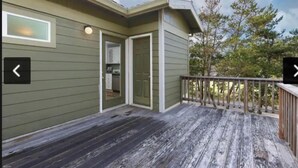 Puinen terassi, jossa on metallikaide, ovi, joka johtaa autotalliin, ja ikkuna rakennuksen sivulla.
