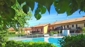 A residential area with a swimming pool surrounded by lush greenery and houses with balconies. - Casa Ruby - Pool and tennis court Lazise/Pacengo (Lazise)