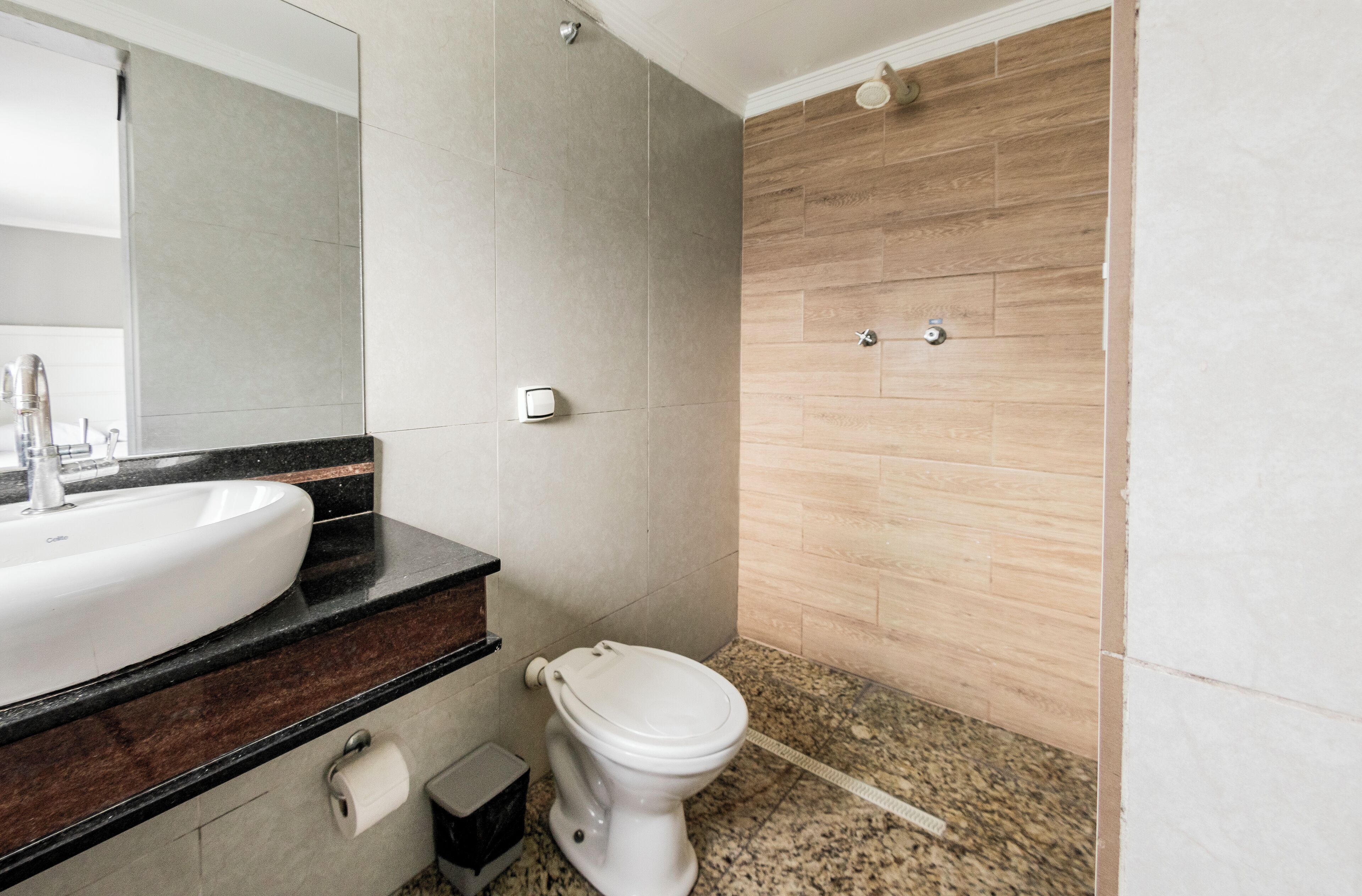 A bathroom with a white sink, dark countertop, and a toilet.
