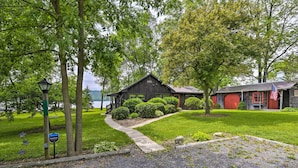 Un chalet rustique avec une façade en bois, une porte rouge et un petit jardin.