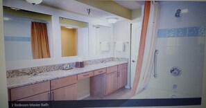 Enjoy a spacious 2-bedroom master bath with a large vanity area, shower, and bathtub featuring a seat.