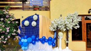 A yellow building with a blue and white decorative archway, white flowers, and a sign reading "Pension Guesthouse". - Pensiunea GuestHouse (Stănești)