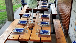 A wooden picnic table set outdoors with blue napkins, glasses, and a white vase. - Pensiunea GuestHouse (Stănești)