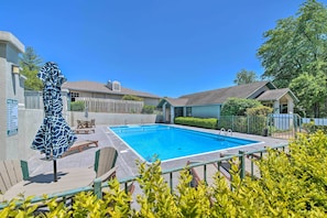 Une piscine entourée d’une clôture, avec une chaise et un banc.