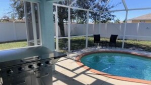 A backyard with a pool, a grill, and outdoor furniture. - Minutes from the beach! Private pool and game room (Cape Coral)