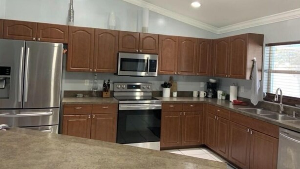 A modern kitchen with stainless steel appliances, wooden cabinets, and a granite countertop. - Minutes from the beach! Private pool and game room (Cape Coral)
