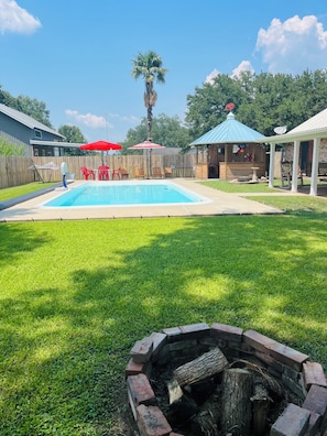 A backyard with a swimming pool, a fire pit, and outdoor furniture. - In the heart of Cajun country! Entire home with pool. (Breaux Bridge)