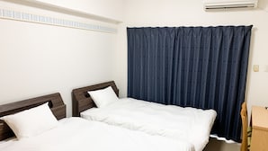 A hotel room with two single beds, a wooden headboard, a desk, and a large window with dark curtains. - HOTEL ARENA (Chatan)
