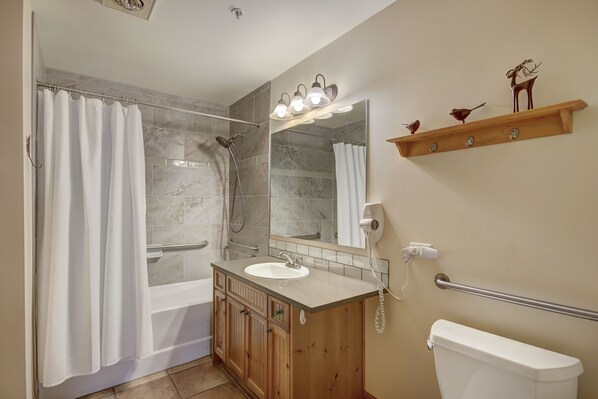 A bathroom with a shower, a sink, a toilet, and a mirror.