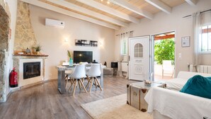 A living room with a stone fireplace, a dining area with chairs, a television, and a view of the outdoors.