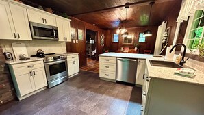 A kitchen with white cabinets, stainless steel appliances, and a wooden ceiling. - Original log cabin on 3 private acres (Boswell)
